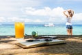 Relaxing girl, opened empty notepad is on the table with sunglasses, phone and headphones at the tropical sea background