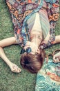 Relaxing in grass. Top view of beautiful young woman in sunglasses and pareo lying on the green grass with beach bag in Royalty Free Stock Photo