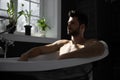 Relaxing handsome man with beard in bathtub