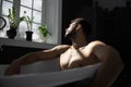 Relaxing handsome man with beard in bathtub