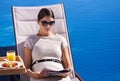 Relaxing while on holiday. A posh young woman reading a magazine while sitting on a deck chair. Royalty Free Stock Photo