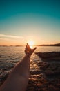Relaxing image of a male hand in front of a massive sunset in the coastline