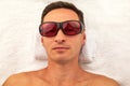 Relaxing man with glasses in spa salon laying on white towel Royalty Free Stock Photo