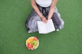 Relaxing moments, Young woman reading a book while sitting on the grass