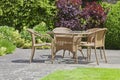 Relaxing patio wicker chairs, round table in a patio summer garden .