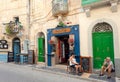 Relaxing people in front of small city cafe on historical street with wooden doors and vintage decorations
