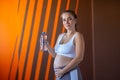 Relaxing pregnant woman is drinking fresh water from plastic bottle in a gym Royalty Free Stock Photo