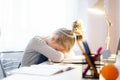 Relaxing. Pretty little girl sleeping over her books while sitting at the table and doing homework Royalty Free Stock Photo