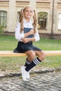 Relaxing in school yard. Student adorable child in formal uniform relaxing outdoors. Schoolgirl relaxing sit on bench Royalty Free Stock Photo