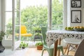 Relaxing space on a balcony with a vibrant yellow chair and homegrown plants and herbs outside a scandinavian dining room