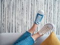 Relaxing Teenager`s feet in different colors beige and blue casual new sneakers on cozy comfortable living room sofa over striped Royalty Free Stock Photo