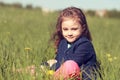 Relaxing thinking cute kid girl sitting in green grass in sunny Royalty Free Stock Photo