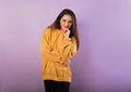 Relaxing thinking smiling sporty woman posing in fashion yellow hoodie with hood on the head on purple bright background  Happy Royalty Free Stock Photo