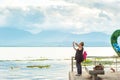 Relaxing tourist women standing on the terrace at lakeside and enjoying lake view with camera, soft sunset shining through a cloud