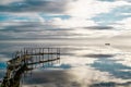 Relaxing view of a reflected blue sky with clouds, a ramshackle wharf and a fishing boat. Royalty Free Stock Photo