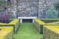 White stone bench by a wall in topiary garden