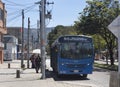 A relaxing woman awaits near to a big SITP blue bus at bus stop in sunny day during bogota no car day