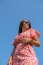 Relaxing young millennial woman in red dress against blue sky. Beautiful smiling girl on summer having fun. Enjoying sun Royalty Free Stock Photo