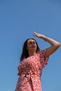 Relaxing young millennial woman in red dress against blue sky. Beautiful smiling girl on summer having fun. Enjoying sun Royalty Free Stock Photo