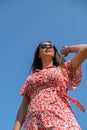 Relaxing young millennial woman in red dress against blue sky. Beautiful smiling girl on summer having fun. Enjoying sun Royalty Free Stock Photo