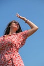 Relaxing young millennial woman in red dress against blue sky. Beautiful smiling girl on summer having fun. Enjoying sun Royalty Free Stock Photo