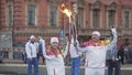 Relay race Sochi Olympic torch in Saint Petersburg. Two torchbearers hold flame, wave hands.