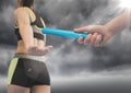 Relay runner and hand with blue baton and flare against stormy sky Royalty Free Stock Photo