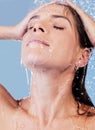 Release your stress with a long, warm shower. Studio shot of a young woman taking a shower against a blue background.