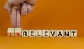 Relevant or irrelevant symbol. Businessman turns wooden cubes changes the word irrelevant to relevant. Beautiful orange table