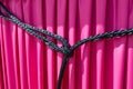 Reliable node close-up. Strong black nylon rope knotted on magenta background. Symbol of strong, reliable connection