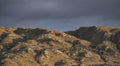 The relief of mountain hills at sunset illumination in the evening against the background of rain clouds Royalty Free Stock Photo