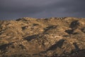 The relief of mountain hills at sunset illumination in the evening against the background of rain clouds Royalty Free Stock Photo