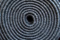 Relief texture of rolled up grey textile carpet as background.