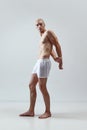 Relief torso. Full-length portrait of handsome young man with blonde hair, muscular body posing in underwear against Royalty Free Stock Photo