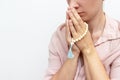 Religeous caucasian young woman praying and holding rosary in hands on white background, copy space