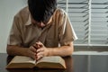 Religion concept, Young asian man reading bible and raising hands to prayer for believe in goodness Royalty Free Stock Photo