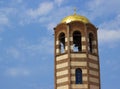 Religion symbol. Beautiful church tower with cross, toller and red tile roof against a bright blue sky with flying birds and Royalty Free Stock Photo