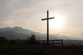 Religion theme, view of catholic cross silhouette, with fantastic sunset and mountains as background. Toned image Royalty Free Stock Photo