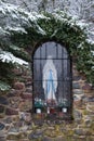 Religions statue in window surrounded by snowy plants