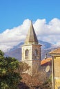 Religious architecture. Bell tower of village church against sky and mountains. Montenegro, Tivat, Donja Lastva village Royalty Free Stock Photo