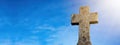 Religious Background - Blue cloudy sky withold weathered stone cross, illuminated by the sun Royalty Free Stock Photo