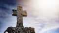 Religious Background - Blue cloudy sky withold weathered stone cross, illuminated by the sun Royalty Free Stock Photo