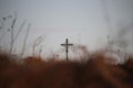 Religious background with blurred brown autumn grass and a cross further on. Royalty Free Stock Photo