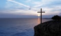 Religious christian cross standing on rock in the sea