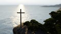 Religious christian cross standing on rock in the sea