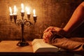 Religious female crossed hands in prayer with bible and candle Royalty Free Stock Photo