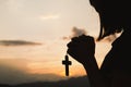 Religious concepts. Silhouette of a girl holding a crucifix to God. Morning with beautiful sunrise, Symbol of Faith. Christian