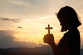 Religious concepts. Silhouette of a girl holding a crucifix to God. Morning with beautiful sunrise, Symbol of Faith. Christian Royalty Free Stock Photo