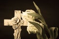 Isolated ornate religious cross with a flower on a dark background. Moment of grief at the end of a life. Last farewell. Royalty Free Stock Photo