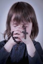 Religious education education of child. Little cute girl praying and holding a rosary